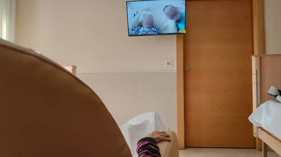 Persona mayor viendo fotos familiares en el televisor de la habitación